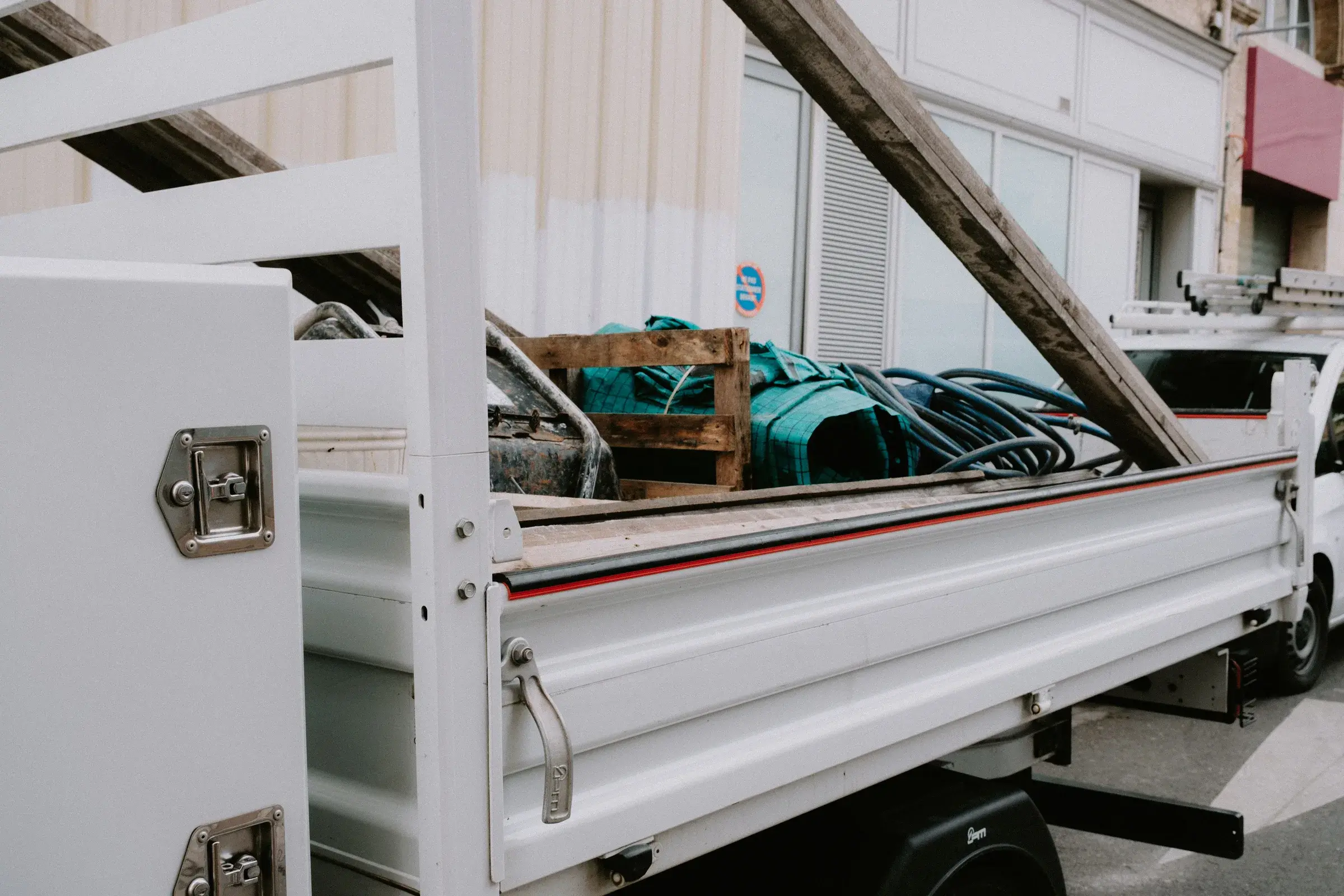 Camion utilitaire blanc chargé de matériaux bâchés