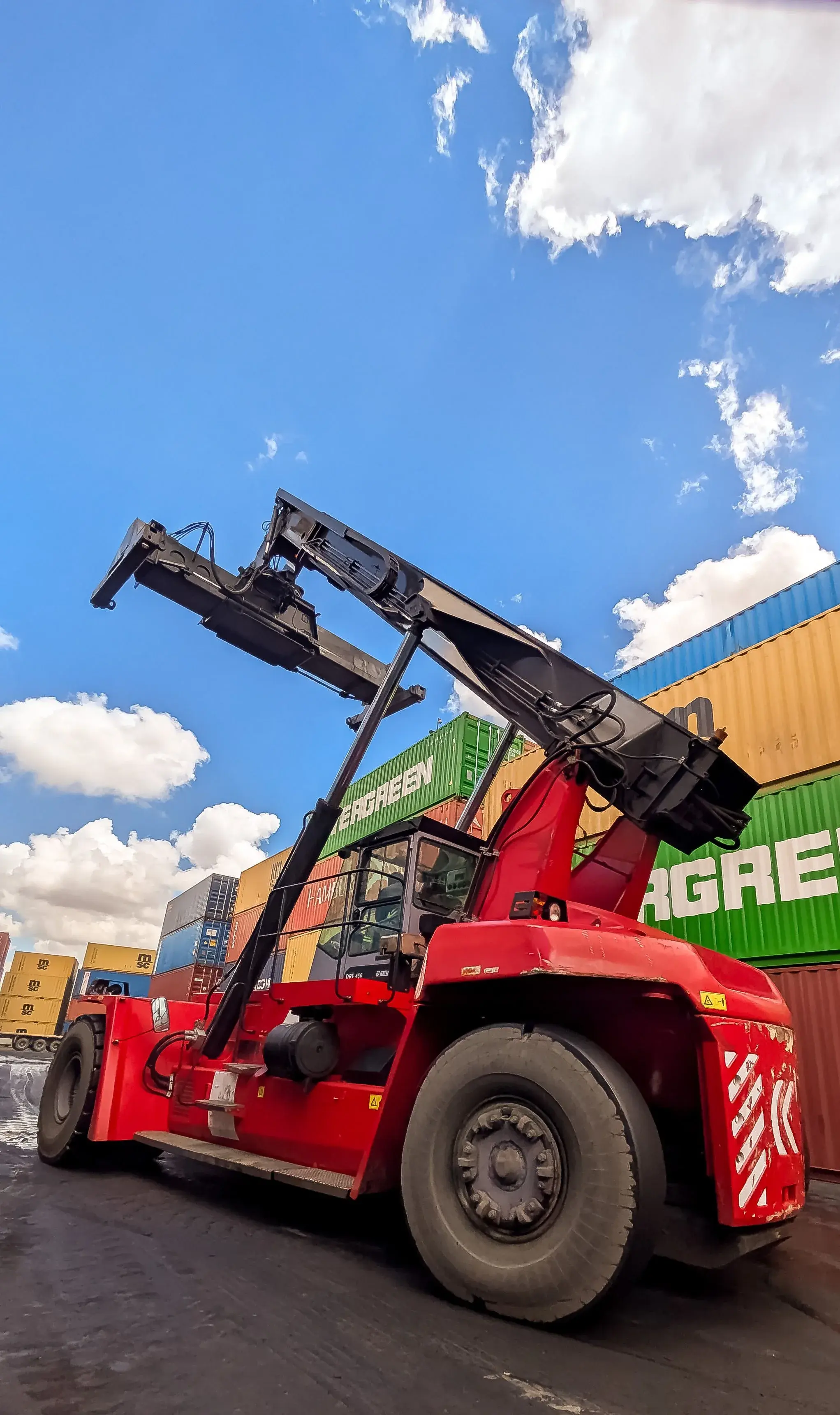 Reach stacker soulevant un conteneur sur un terminal portuaire